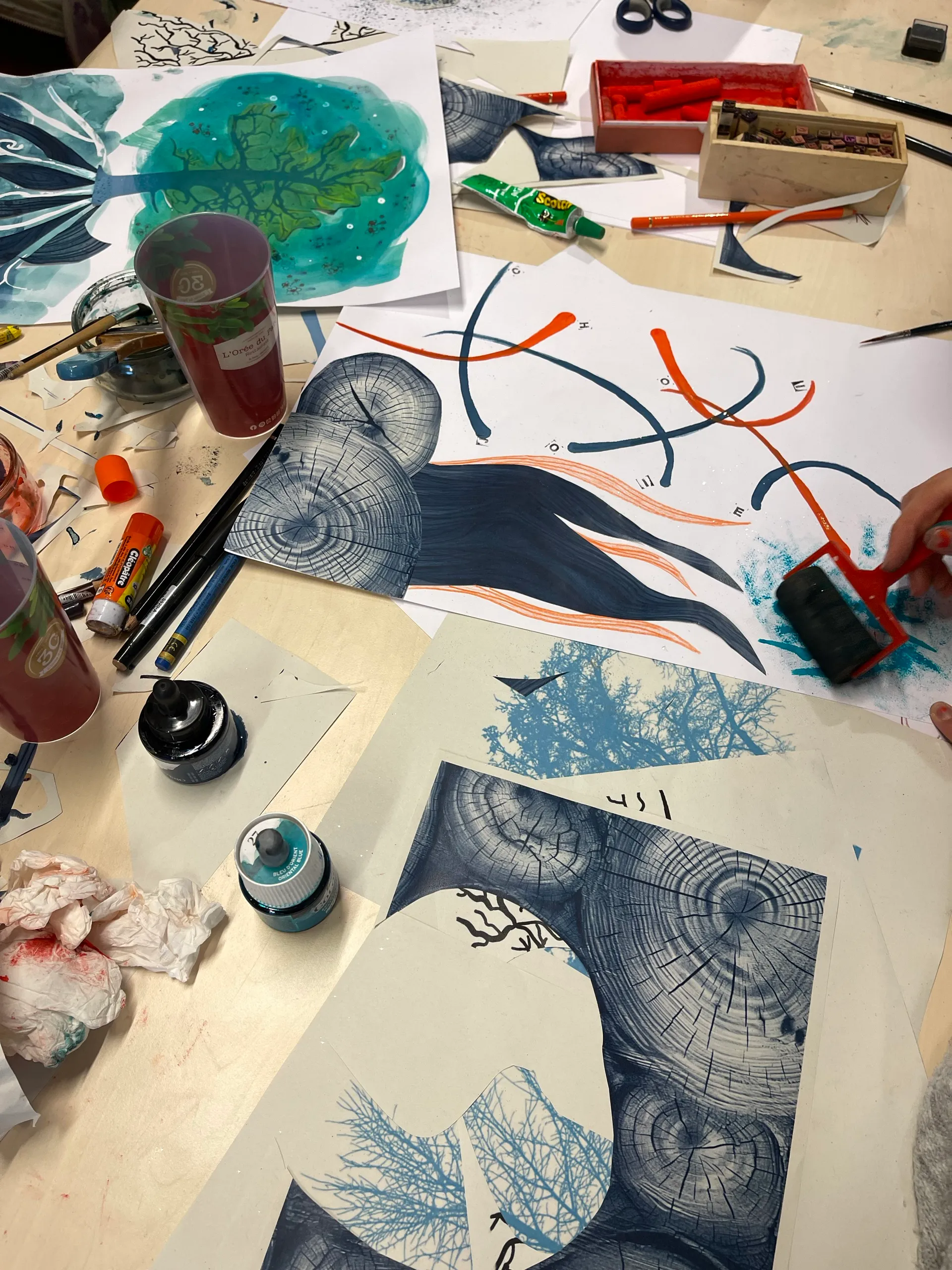 Table de travail couverte de linogravures et d’encres bleues et orange